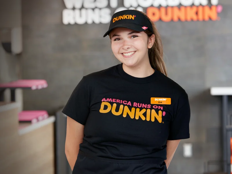 A smiling PPP Donuts Network crew member behind the counter